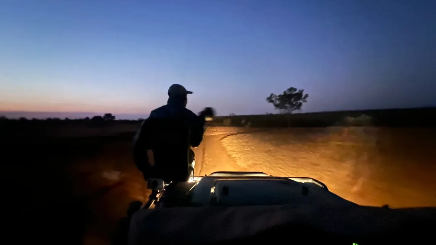 Guide standing in an open safari vehicle during a night drive in Kruger