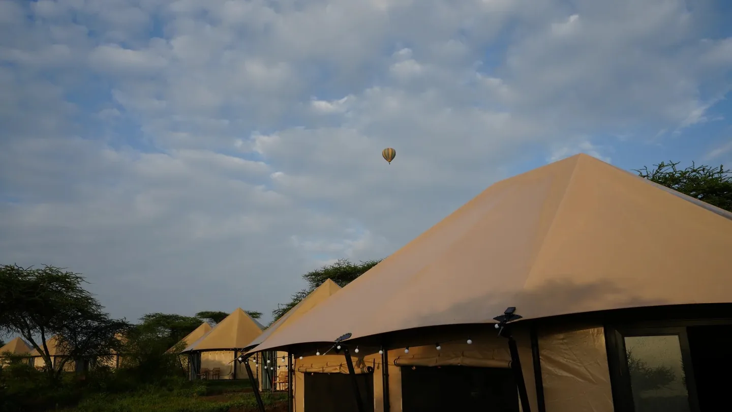 Canvas suites at Malaika Luxury Camp in Ndutu with a hot-air balloon in the sky