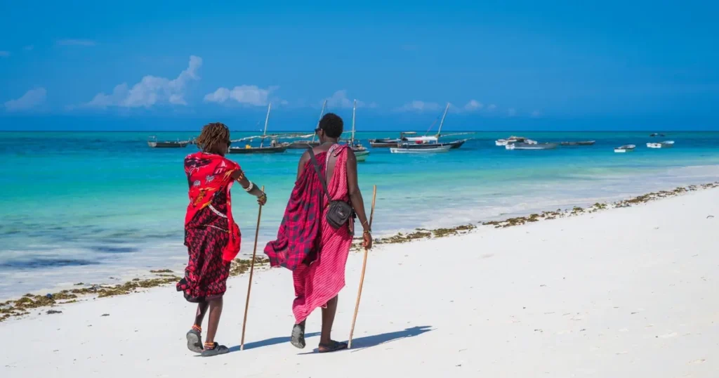 Two people walking along a white-sand beach in Zanzibar